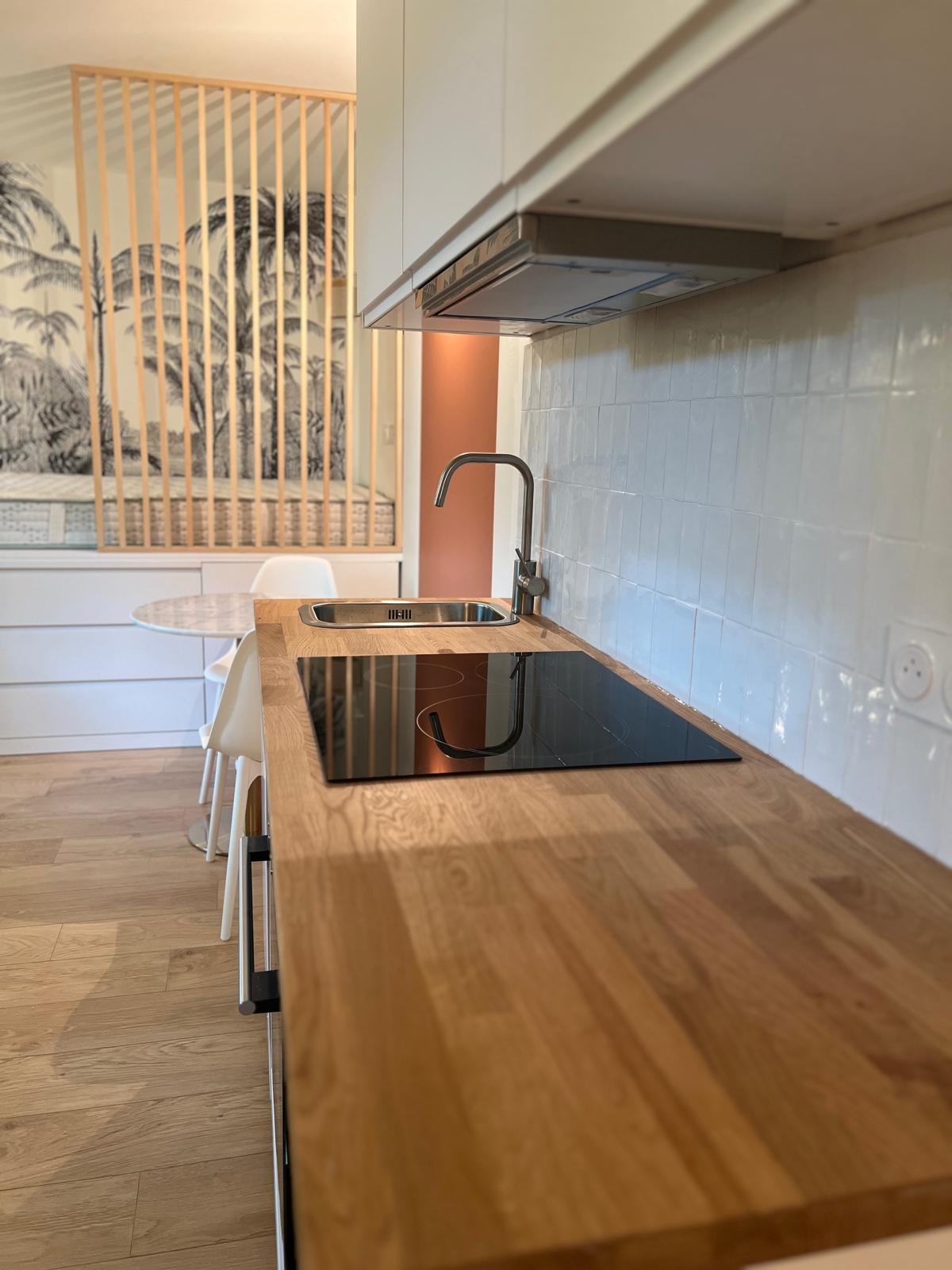 Rénovation d'une petite cuisine moderne avec plan de travail en bois, crédence en faïence blanche et séparation en tasseaux de bois par BatiPrestige.